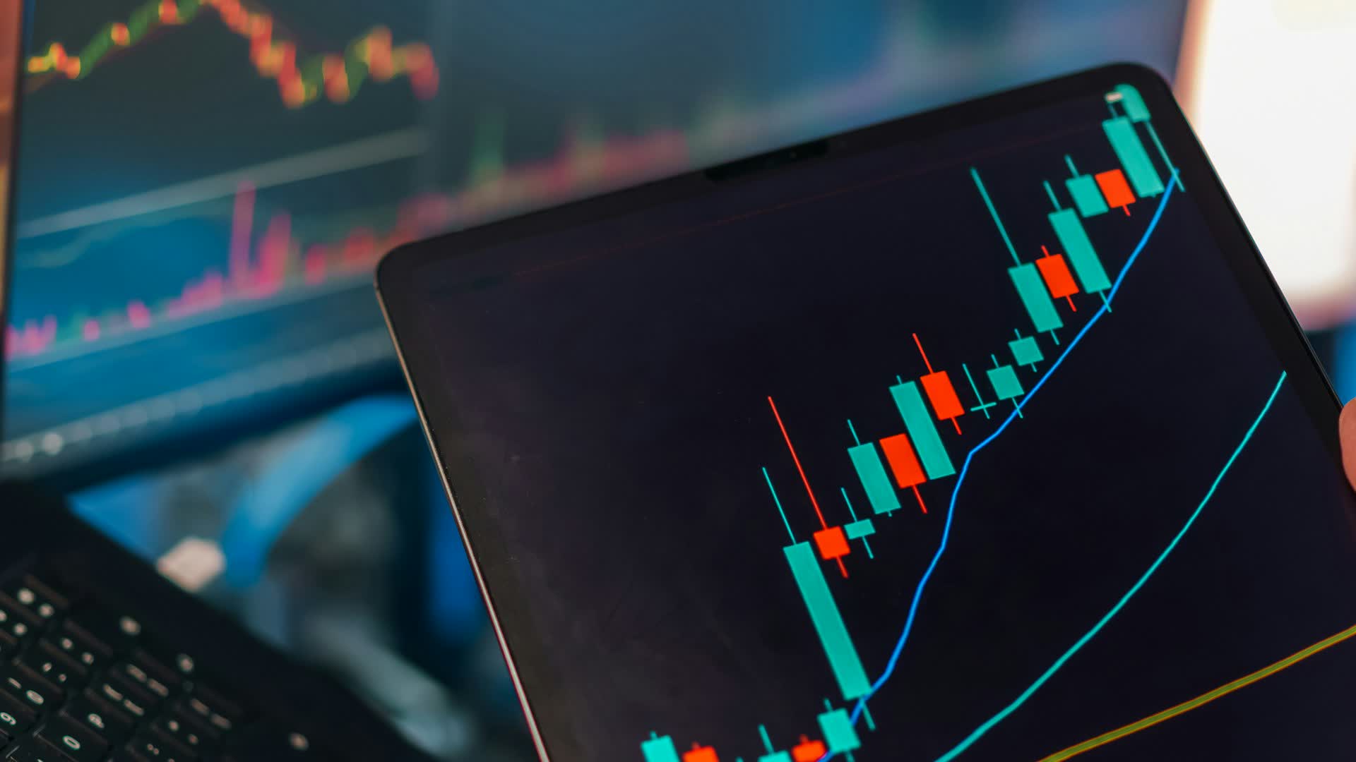 Financial market charts on a tablet and trading screens